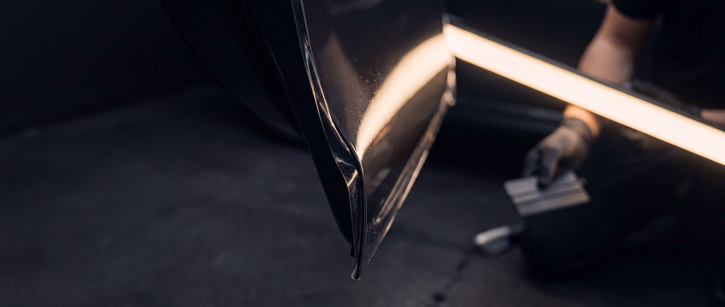 A flawless film edge wrapped around a car door edge, lit by a raking light.